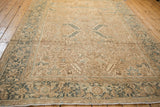 Angled view of a vintage Heriz carpet showing the dusty teal Turtle Samovar border against the distressed sand-colored field.