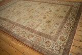 Faded beige, red, and green palmette and serrated leaf motif in the distressed Kashan carpet's border.
