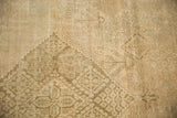 Distressed Joshegan rug close-up, highlighting worn beige pile and faded stepped patterns.