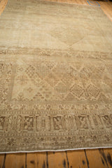 Distressed Joshegan carpet, a geometric coffee brown border with faded field motifs.