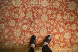 Distressed Kashan carpet with faded cherry red field of palmettes and scrolling vines.