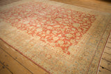 Distressed vintage Kashan rug corner, with faded cherry red floral field and ivory meandering vine border.