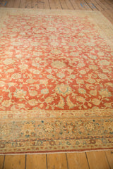 Faded cherry red field with ivory palmettes and blossoms on a distressed Kashan rug.