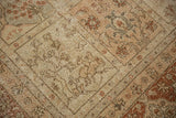 Distressed vintage Tabriz carpet showing botanical panels in faded ivory, beige, and chestnut rust.