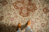 A close view of the distressed Tabriz rug's low pile, highlighting its mostly even wear and terracotta medallion.
