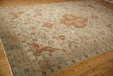 Corner view of a distressed Tabriz carpet's floral border in seafoam green and copper tones.
