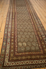 Distressed vintage Kurdish runner with muted boteh patterns and pomegranate red geometric borders.