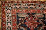 Corner detail of an antique Malayer rug showing a signature cartouche and red and ivory Herati borders.