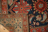A folded corner of the antique Malayer rug shows its hand-knotted foundation beneath the worn, detailed pile.