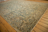 Distressed Malayer carpet corner showcasing dusty teal and beige scrolled floral patterns.
