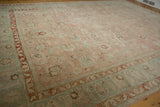 Distressed vintage Tabriz carpet close-up, showing Herati style border and faded rose field.