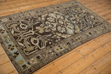 Distressed Mehriban rug corner showing geometric arabesques in charcoal, ivory, and blue.