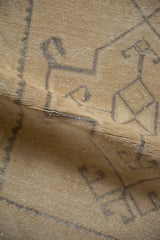 Distressed pile texture of a vintage Oushak rug, showing beige and gray geometric motifs.