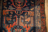 Geometric animal and floral motifs in rust and sapphire blue on a hand-knotted Malayer rug.