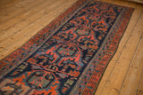 A vintage Malayer runner with geometric arabesques in navy blue and madder rust, viewed along its length.