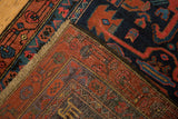 Corner of a Persian Malayer runner folded to show the hand-knotted foundation and low pile.