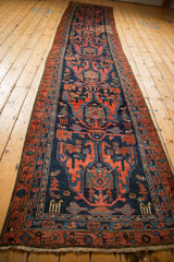 Vintage Malayer runner shown full-length from an angle, highlighting its geometric animal motifs on a navy field.