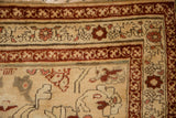 Antique Karabagh rug corner detail showing distressed beige, apricot, and wine red floral borders.