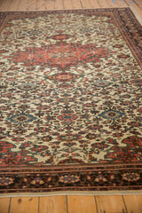 Low-angle view of an antique Farahan Sarouk's dense floral field and time-softened low pile.