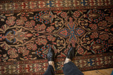 Scrolled vines with blush and sapphire blue blossoms on a vintage Malayer runner's deep charcoal field.