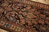 Scrolled vines with serrated leaves and blossoms in blush, blue, and sand on a charcoal brown rug pile.