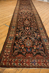 Long vintage Malayer runner shown at an angle, displaying its repeating floral and vine pattern.