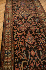 Angled view of a vintage Malayer runner, showing the detailed border and scrolled vine field.