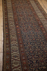 Angled view of an antique Malayer runner's serrated leaf trellis field and meandering borders.