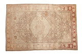 Distressed vintage Kayseri rug with a scalloped medallion and heavy abrashes in soft beige, ivory, and dusty rose tones.