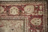 Worn texture of a distressed Kayseri carpet corner with pomegranate red and beige floral borders.
