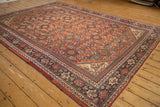 Vintage Mahal carpet with a brick red Herati design and navy Samovar border, seen from an angle.
