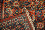 Folded corner of a vintage Mahal carpet revealing the Samovar border, Herati field, and fringe.