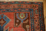 Close-up on an antique Heriz rug corner revealing turtle-style motifs and intricate sapphire blue borders.