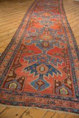 Angled perspective down the length of an antique Heriz runner with repeating red and blue turtle medallions.