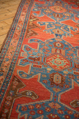 Angled detail of a Heriz runner showing geometric turtle medallions and the sapphire blue side border.