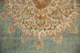 Worn pile detail showing terracotta and brown floral motifs on the carpet's abrashed blue field.