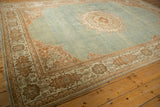 Angled view of the vintage Persian rug's corner, showing terracotta and ivory motifs on a dusty blue field.