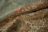 Folded vintage Persian rug showing the soft, worn texture and abrashed blue and terracotta tones.