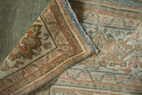 Folded corner of a distressed Persian rug showing its hand-knotted back and secured selvage.