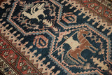 Pictorial designs of a bird and person on horseback on the dark teal field of an antique Malayer rug.