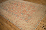 Angled view of a distressed Kashan carpet showing the low pile and faded brick red and blue arabesques.