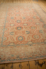 Angled view of the distressed Kashan carpet showing faded red arabesques and blue palmettes.