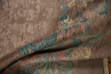 Folded vintage Fette-Li rug showing textural beige field with seafoam, dusty rose blossoms.