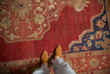Vintage Oushak carpet with heavily abrashed red ground, floral motifs, and cobalt blue spandrel.