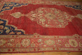 Abrashed red ground and cobalt blue corner spandrel with floral motifs on vintage Oushak rug.