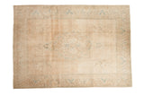 Distressed vintage Tabriz carpet with ornate central medallion in beige, ivory, and soft seafoam blue.