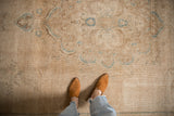 Faded floral patterns on a distressed vintage Tabriz carpet with neutral tones.