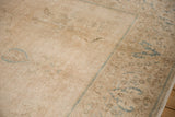 Distressed beige pile of a vintage Tabriz carpet, showing faded seafoam blue floral motifs.