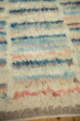 Soft, shaggy wool texture of a Moroccan design carpet with blue and dusty rose stripes.