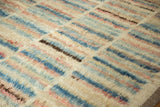 Soft, shaggy wool pile of an Afghani rug with abstract blue, rose, and ivory stripes.